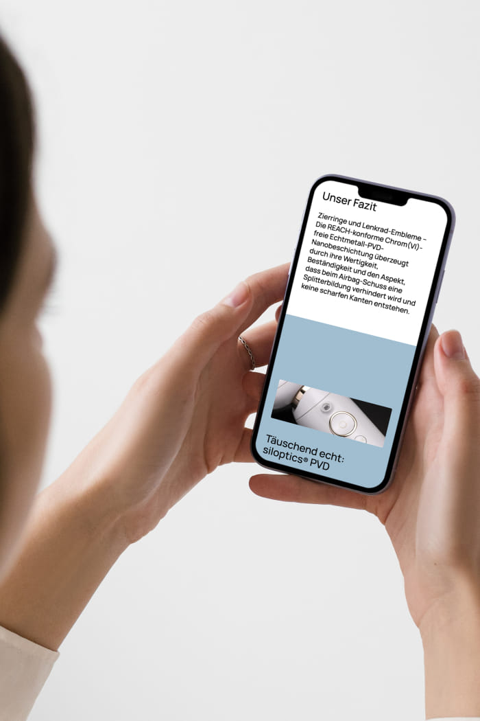 Man blickt einer Dame über die Schulter und sieht, wie sie ein Handy in ihren Händen hält. Auf dem Bildschirm des Handys ist die Silcos-Website geöffnet, die einen kleinen Einblick in das Webdesign bietet.