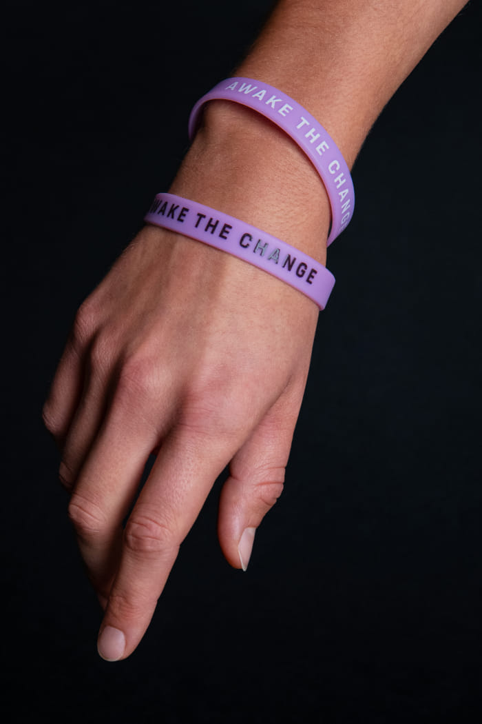 Eine linke Hand auf dunklem Hintergrund, der Fokus liegt auf zwei Armbändern, die im Design des Events gebrandet sind.