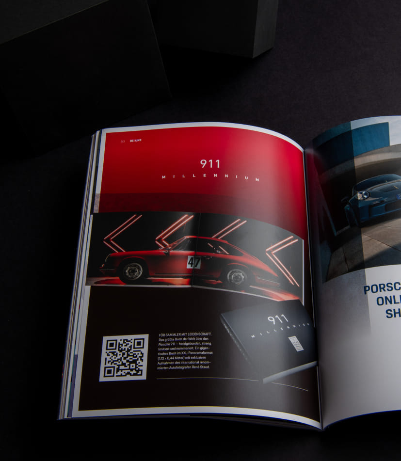 Aufgeschlagene Porsche Times zeigt eine Doppelseite zur Sonderedition 911 Millennium mit rotem Porsche und stilisierter Lichtinszenierung.