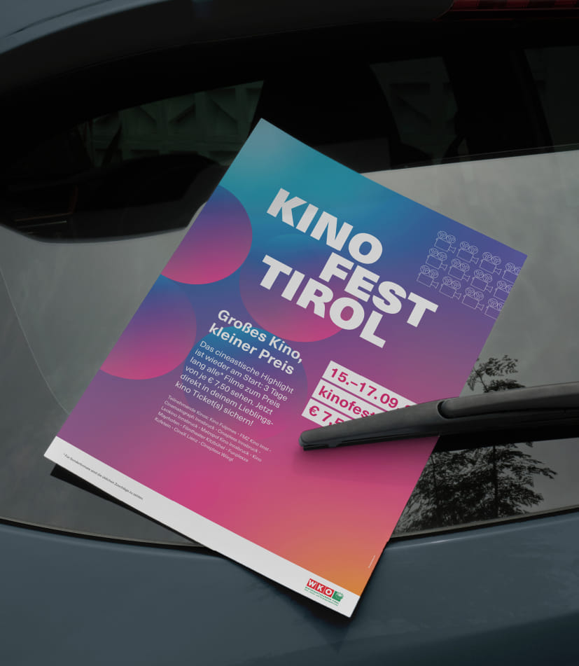 Auf der Heckscheibe eines dunklen Autos ist der Event Flyer des Kino Fest Tirol eingeklemmt.