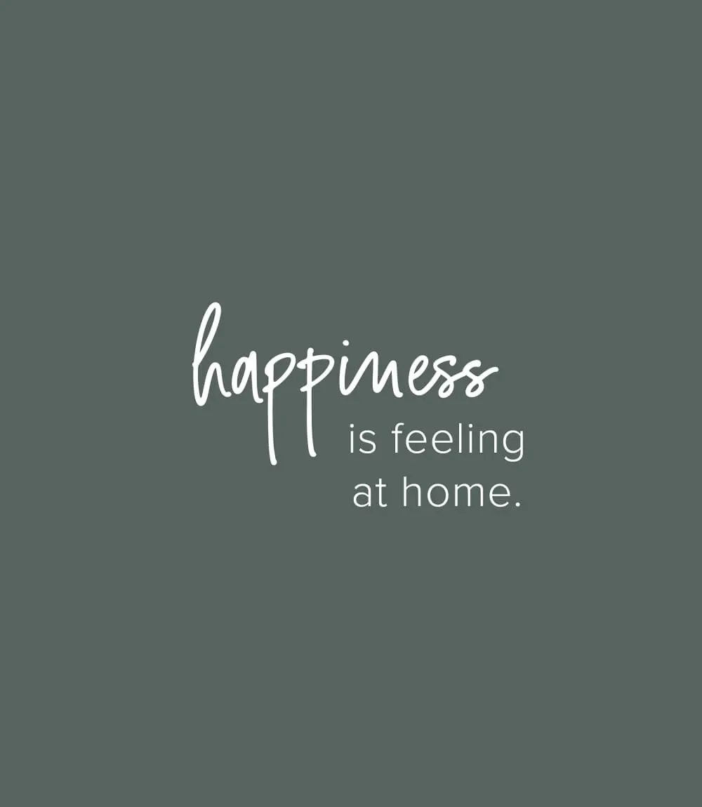 Minimalistisches Design-Zitat auf grau-grünem Hintergrund mit handschriftlichem Text: happiness is feeling at home.
