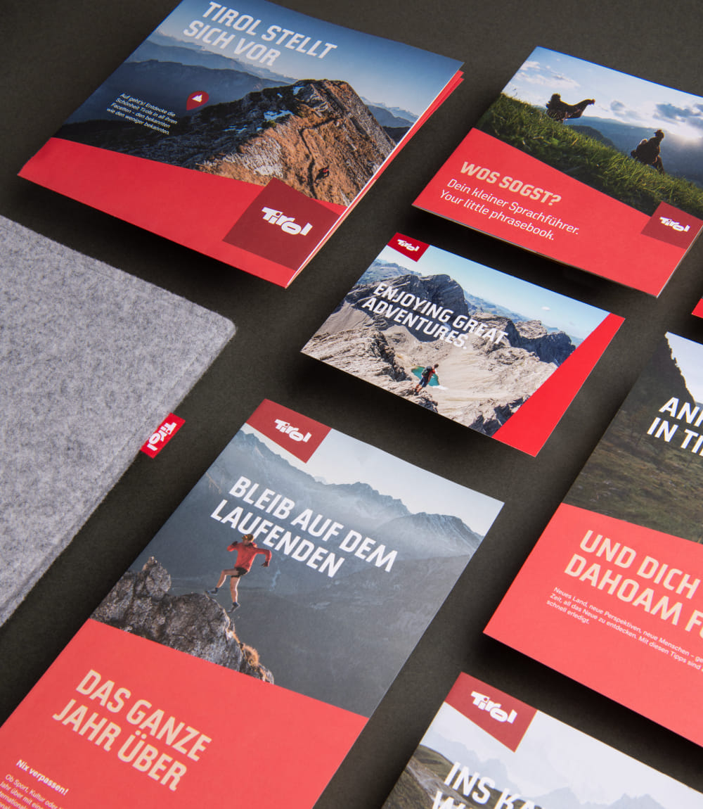 Unterschiedliche Tirol Broschüren auf dunkelgrauer Tischplatte angereiht.