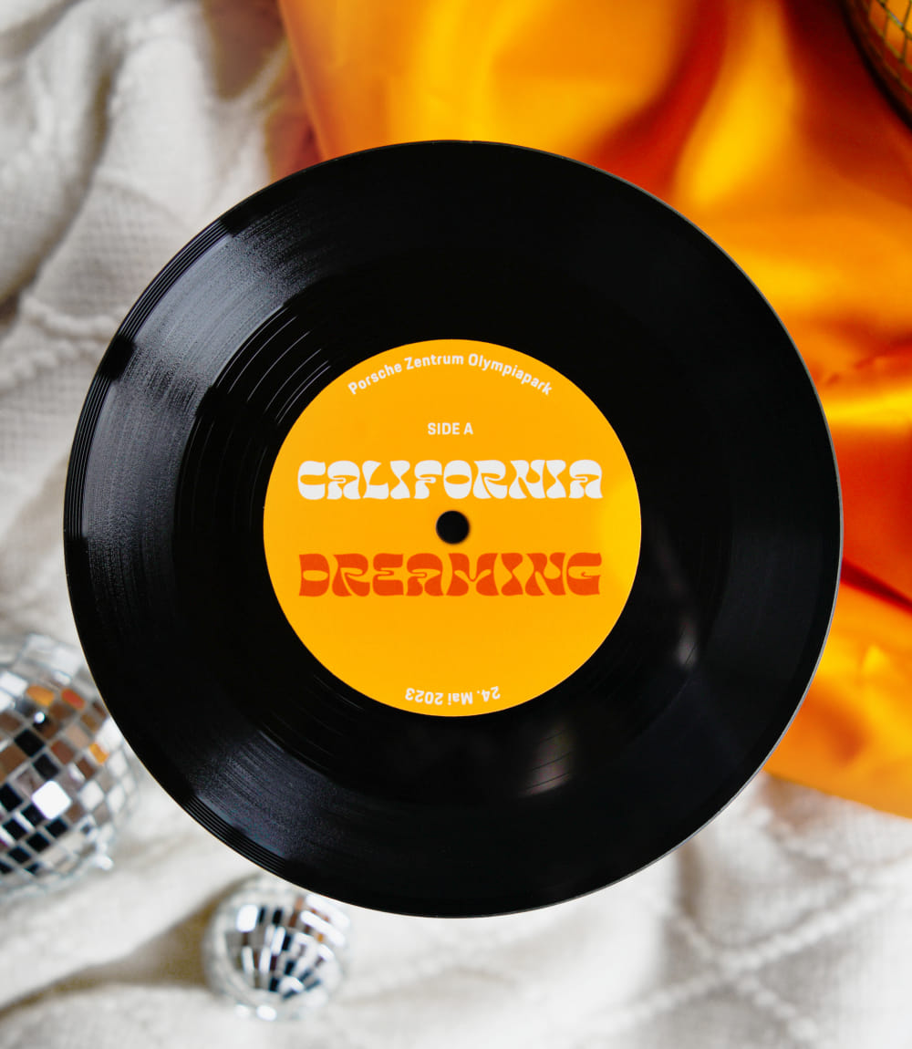 Schwarze Vinyl-Schallplatte mit gelbem Label CALIFORNIA DREAMING im Retro-Stil für das Porsche Zentrum Olympiapark. 
