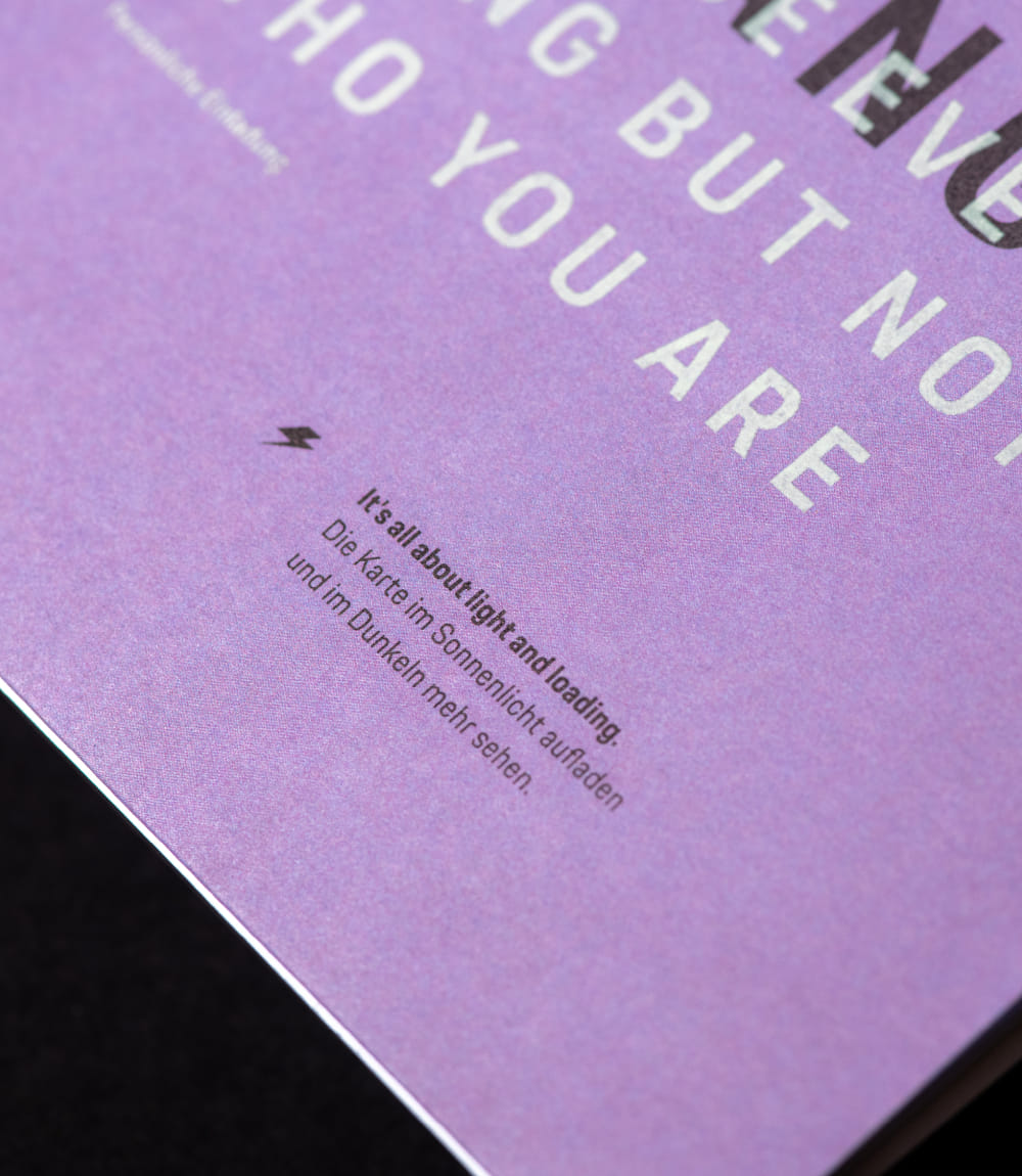 Eine Detailaufnahme der Einladungskarte zeigt die untere Ecke mit der Aufschrift 'It's all about light and loading.