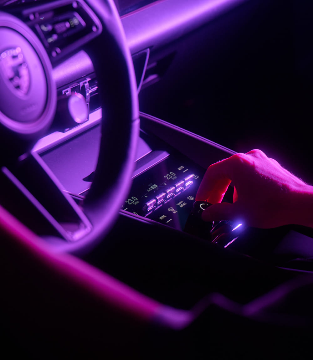 Im Fokus sind das Lenkrad und die umliegende Innenausstattung eines Porsche.