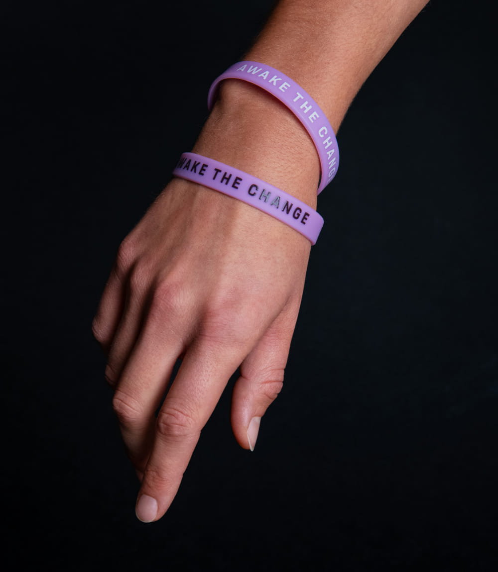 Eine linke Hand auf dunklem Hintergrund, der Fokus liegt auf zwei Armbändern, die im Design des Events gebrandet sind.