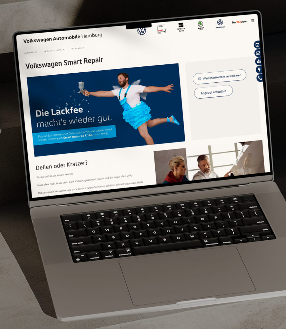Ein offenes MacBook das auf dem Screen sichtbar die Einstiegsseite von Volkswagen Automobile Hamburg mit der Werbeanzeige für Volkswagen Smart Repair. Auf blauem Hintergrund ein bärtiger Mann in blauem Tutu Feenoutfit mit einer Sprühflasche aus der scheinbar weiße Sternchen sprühen. Darunter die Schrift: Die Lackfee macht´s wieder gut und eine entsprechendes Package für Smart Repair. 