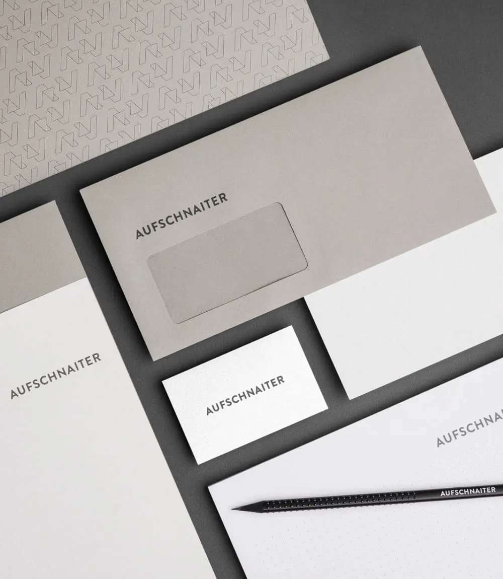 Detailansicht der Geschäftsausstattung von Aufschnaiter mit Briefpapier, Kuvert, Visitenkarte und Bleistift
