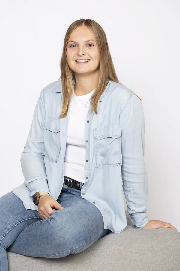 Frau mit blonden Haaren sitzt auf einem Sofa.